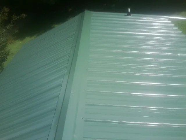 New green metal panels meeting at the ridge of a roof — Flat Roof Repair work by our crew in Millersburg